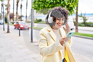 Young middle east woman excutive smiling confident listening to music at street