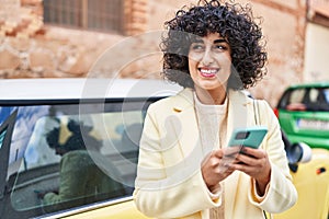 Young middle east woman excutive smiling confident using smartphone at street