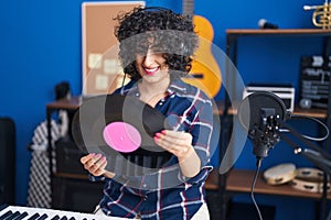 Young middle east woman musician listening music holding vinyl disc at music studio