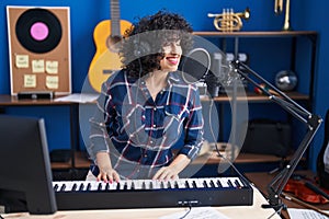 Young middle east woman musician singing song playing piano keyboard at music studio