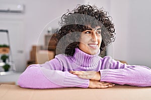 Young middle east woman smiling confident leaning on package at new home
