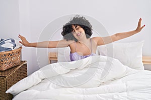 Young middle east woman stretching arms waking up at bedroom