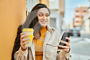 Young middle east woman using smartphone drinking coffee at the city