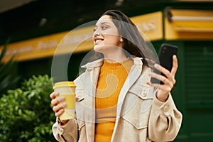 Young middle east woman using smartphone drinking coffee at the city