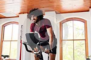 Young middle eastern man doing intense cardio workout on exercise bike at the gym