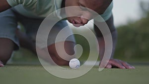 Young middle eastern man playing golf on the golf field. Handsome man blowing on the golf ball which lies in the edge of