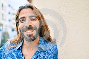 Young middle eastern man smiling happy leaning on the wall at the city