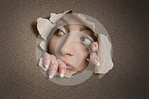 Young Middle eastern woman looking away from ripped paper hole