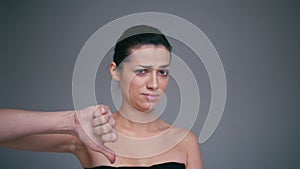 Young milennial woman showing a sign of dislike, isolated on a gray background