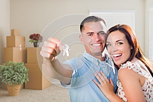 Young Military Couple with House Keys in Empty Room with Packed