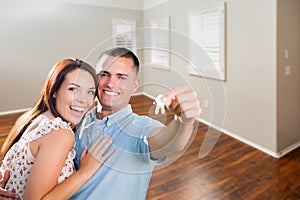 Young Military Couple Showing Off House Keys in Empty Room of New Home