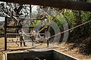 Young military soldiers practising rope climbing during obstacle course