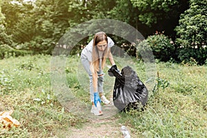 Young millennial caucasian woman cleaning-up public park or forest of plastic garbage. Volunteer picking up plastic