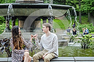 Young Millennial couple pinky promising by fountain