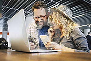 Young millennial couple working together in coworking space with mobile phones and laptop computer. Modern online job lifestyle
