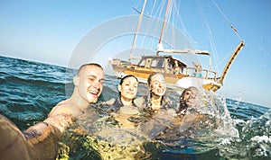 Young millennial friends taking selfie and swimming at sailing boat sea trip - Rich guys and girls having fun in summer party day