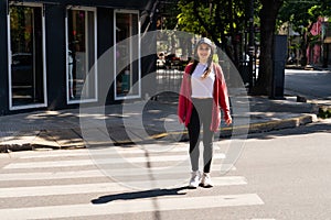 Young millennial woman crossing the street on the pedestrian path