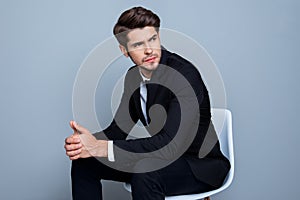 Young minded businessman in black suit sitting on chair