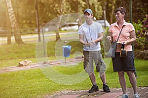 Young minigolf player is preparing for the minigolf game while t