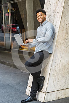 Young Mix-Race American Man working on laptop computer outside office in New York City