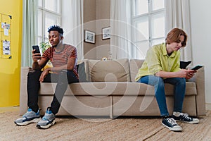 Young mixed couple addicted to smartphones ignoring each other at home. Relationship problems.