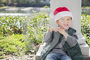 Young Mixed Race Boy Wears Santa Hat Eats Candy Cane