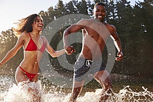 Young mixed race couple running and splashing in a lake