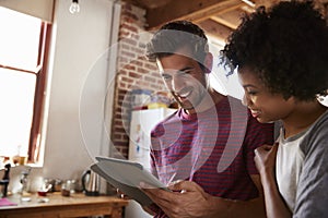 Young mixed race couple using tablet in kitchen, close up