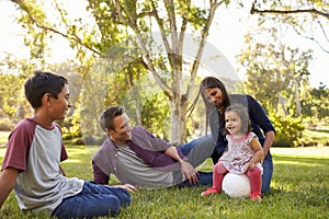 Young mixed race family relaxing with soccer ball in a park