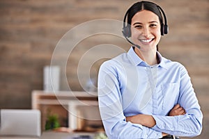 Young mixed race female call center agent standing with her arms crossed wearing a headset answering calls working in an