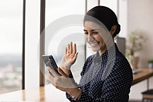 Young mixed race female look at cellphone screen wave hand