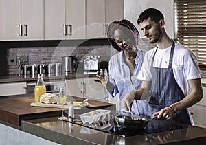 Young mixed race happy couple preparing breakfast in the kitchen cooking