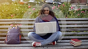 Young mixed race lady writing essay on laptop, studying full of inspiration