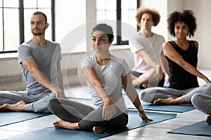 Young mixed race people doing simple seated twist exercise.