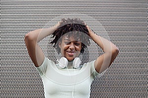 Young mixed race woman with afro hairstyle smiling in urban background. Black girl in casual clothes