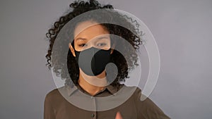 Young mixed race woman in black protective mask showing thumbs up, 4K