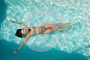 Young mixed-race woman floating in swimming pool