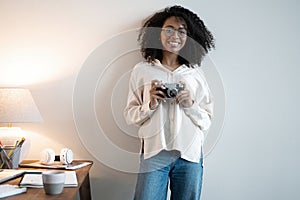 Young mixed race woman photographer with a professional camera in office