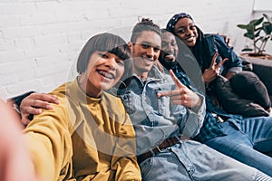 young mixed race woman taking selfie with multiethnic friends doing peace