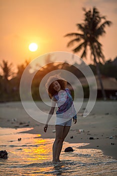 Young mixed race woman walking on the sea beach during amazing sunset.