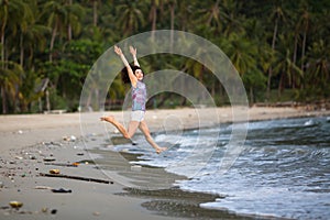 Young mixed-race woman walks along a polluted tropical beach.