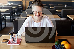 Young mixed race woman working with laptop in cafe. Asian caucasian female studying using internet. Business woman doing