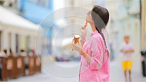 Young model eating ice cream cone outdoors. Summer concept - woamn with sweet ice-cream at hot day