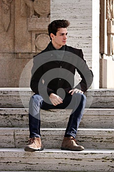 Young model man sitting on marble steps
