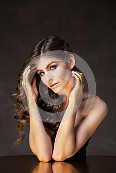 Young model with wavy hair. Golden tint on eyebrows and hands