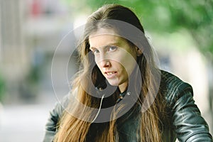 Young model woman with long straight hair wearing leather jacket posing carefree and casual on the street