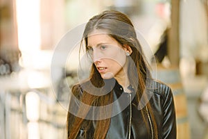 Young model woman with long straight hair wearing leather jacket posing carefree and casual on the street