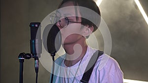 Young modern Asian man in a recording studio singing into a microphone. Asian singer or musician