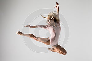 Young modern ballet gymnastics dancer jumping on white background