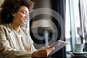 Young modern business black woman working using digital tablet while sitting in the office